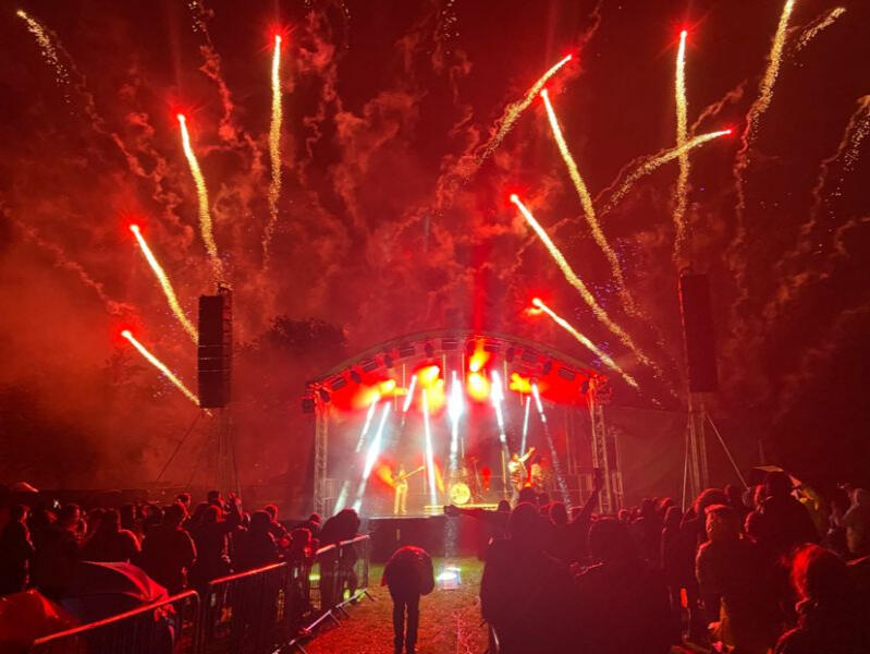 Henley Theatre Services illuminated in red lights and fireworks with a large crowd.