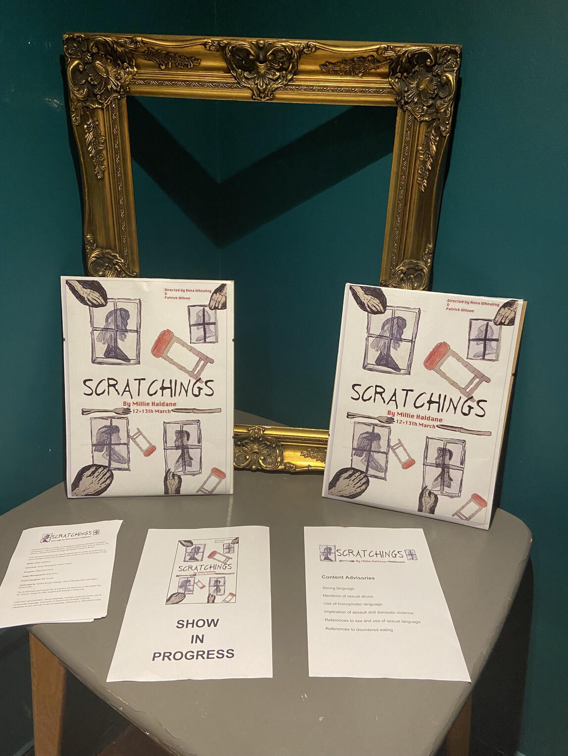 Scratchings Promo graphics on a table with papers saying "show in progress"